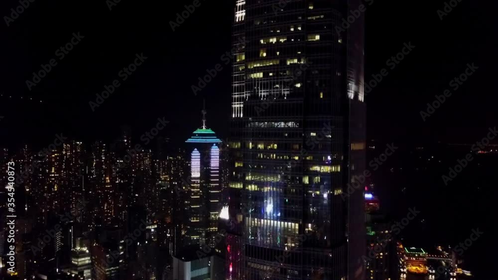 Aerial shot of illuminated skyscrapers in city against sky, drone ascending at night - Hong Kong, China Aerial shot of illuminated skyscrapers in city against sky, drone ascending at night - Hong Kong, China