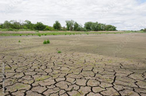 dry pond with cracked earth against a cloudy sky 8