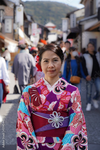 Woman dress in pink kimono walking on street with blur background, portrait orientation.