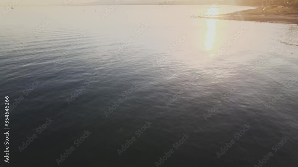 High angle aerial shot of the ocean with tilt up to the horizon and revealing the sunset High angle aerial shot of the ocean with tilt up to the horizon and revealing the sunset