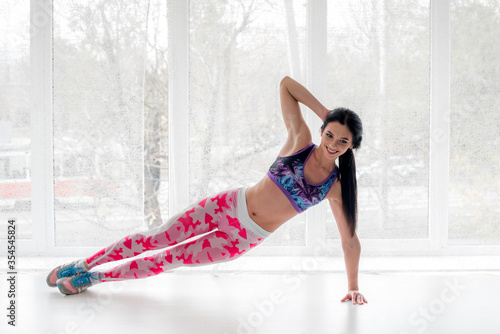 Athletic young girl performs exercises in the Studio on a light background. Fitness  healthy lifestyle