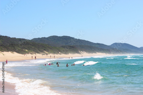 People swimming on long sandy beach © ann gadd