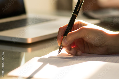Hand of businesswoman writing on paper in office. Writing notes and planning her schedule.