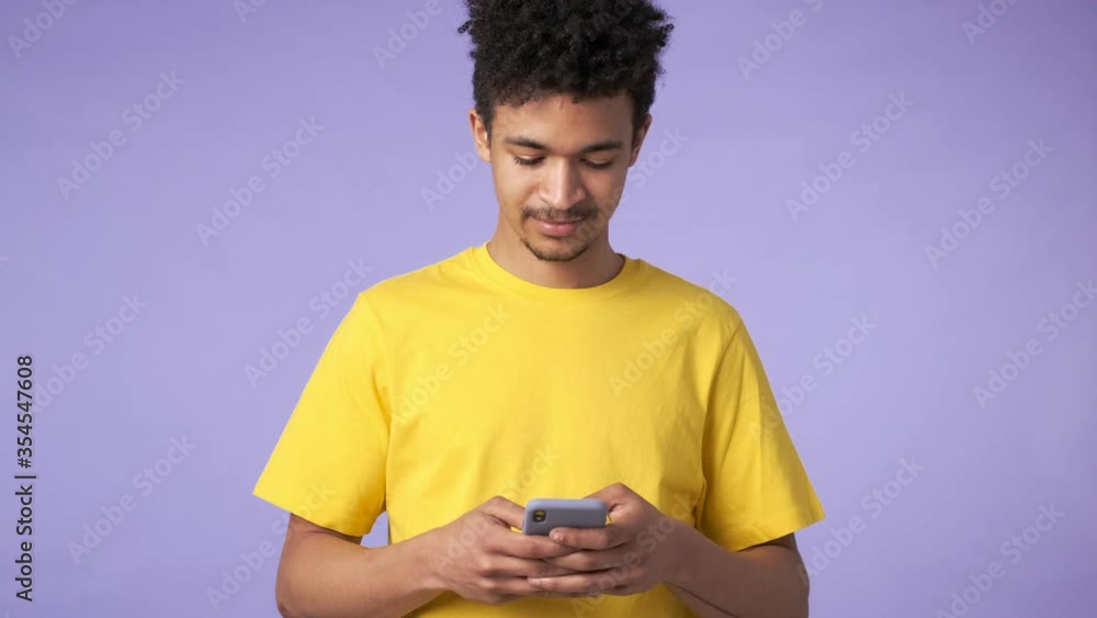 Young african concentrated guy isolated over purple background using mobile phone Young african concentrated guy isolated over purple background using mobile phone