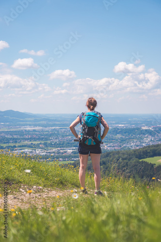 Enjoying the idyllic mountain landscape on Gaisberg: Girl is standing on idyllic meadow and enjoying the view over the far away city of Salzburg