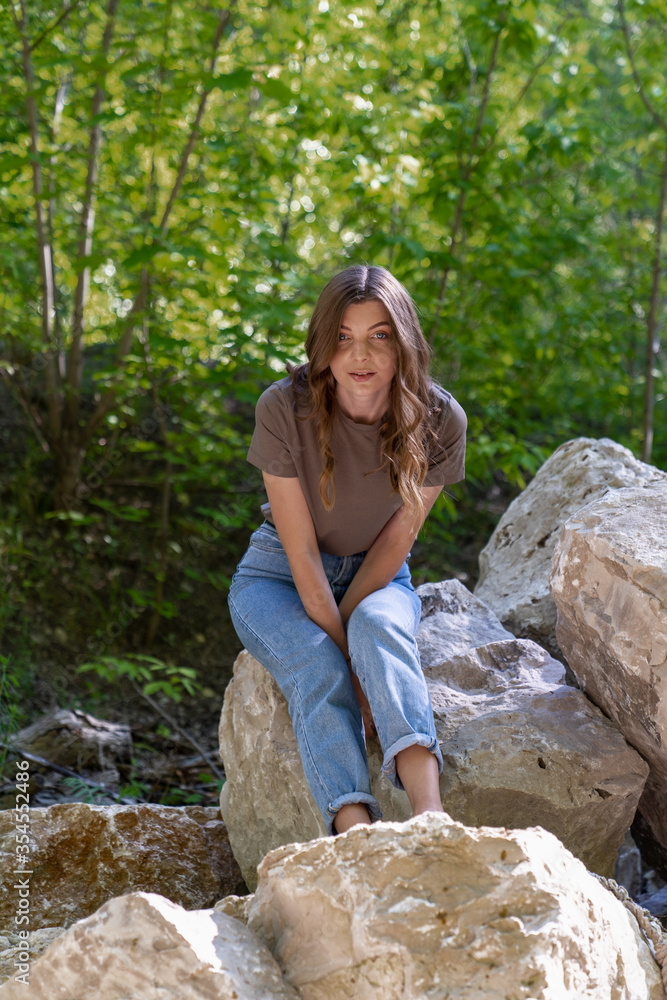 young women are sitting on miles in a forest surrounded by green trees. Peace and calm in the look. young women are sitting on miles in a forest surrounded by green trees. Peace and calm in the look.