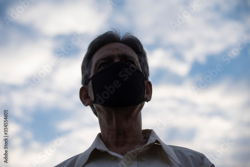 Low angle view of Indian old man with corona virus protective mask below the blue cloudy sky. Home isolation and Indian lifestyle © abir