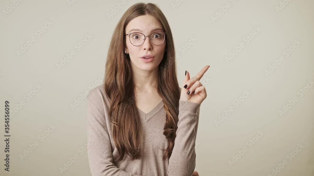 Beautiful young thinking cute pretty woman wearing glasses isolated over grey wall background have an idea pointing Beautiful young thinking cute pretty woman wearing glasses isolated over grey wall background have an idea pointing