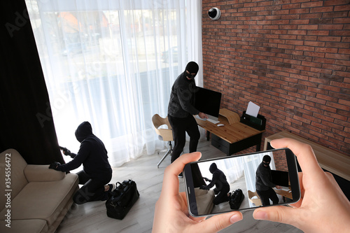 Photography Man monitoring situation at his house with CCTV app on smartphone, closeup