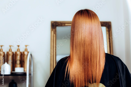 Back view of girl with long and straight redhead hair . Shiny smooth hair. copypast photo