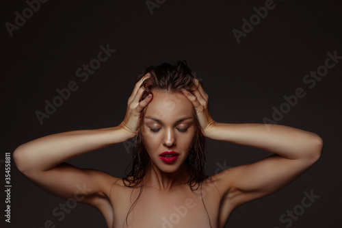 Lovely. Portrait of beautiful stylish woman isolated on dark studio background. Caucasian model with red lipstick, wet hair and shiny skin, bright make up. Beauty, fashion, emotions concept.