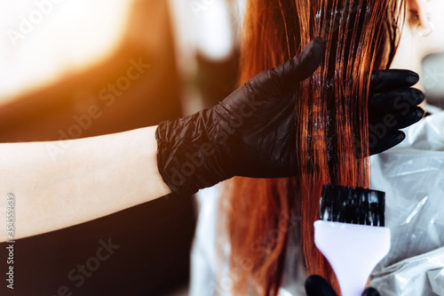 Hairdresser applies a redhead hair mask to the woman in the beauty salon. Botox and keratin hair straightening procedure