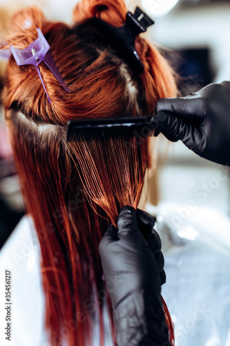 The hairdresser applies nutritious and healing components to damaged hair, applying botox to the hair, combs every strand