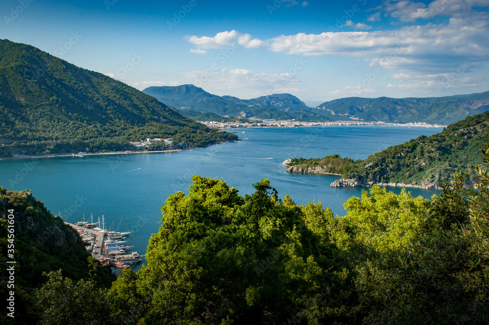 A view from the hills between Turunc and Icmeler, Turkey looking toward Marmaris amid lush pine forested hills and azure blue sea.