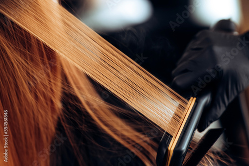 The hairdresser pulls the client hair, after washing his head, applying nutrients to the hair and drying the hair with a hair dryer, botox hair, restoring and nourishing the hair