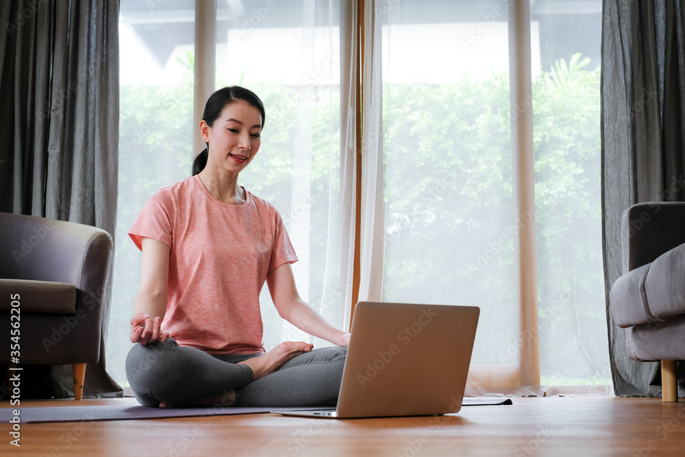 Asian woman studying yoga course online
with using computer laptop while stay at home. Asian woman studying yoga course online
with using computer laptop while stay at home.