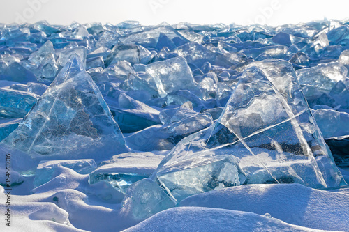 Luminous transparent triangle blue ice blocks among field of broken ice, beautiful winter landscape or background