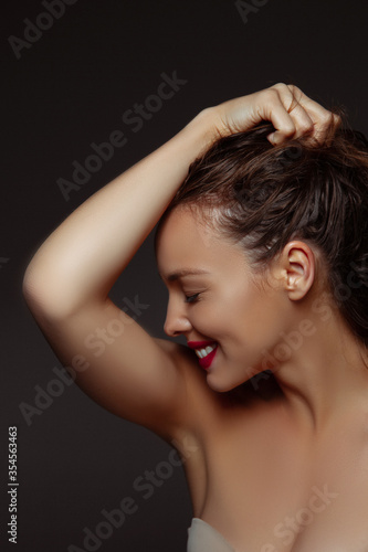 Natural purity. Portrait of beautiful stylish woman isolated on dark studio background. Caucasian model with red lipstick, wet hair and shiny skin, bright make up. Beauty, fashion, emotions concept.