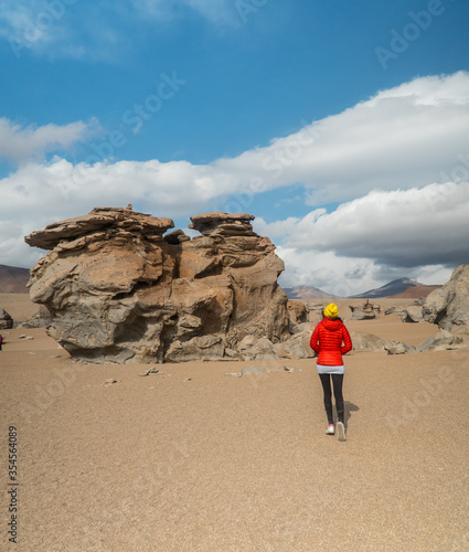 Tourist woman hiking Rocky landscape mountain. Dry  Barren desert  snowcapped mountains wilderness. Mountain range view. Salt Flats  Uyuni  Bolivia. Copy space  Rocks  blue sky  nature  hiker