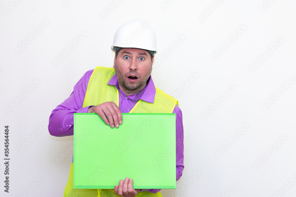 Portrait of curious surprised architect in a construction helmet holding a folder, free place mock up banner advertisement.Studio shoot.