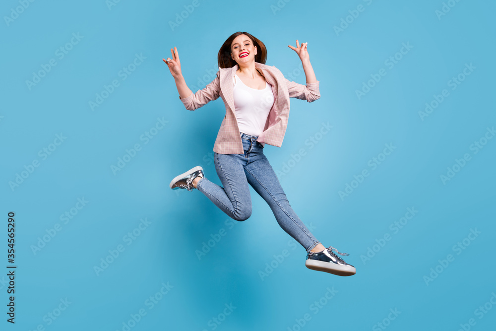 Full body photo of cheerful lovely pretty girl jump make v-sign wear plaid blazer sneakers isolated over blue color background