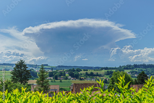 Magnifique cumulus en formation au-dessus du jura de forme conique au-dessus d'un paysage de la suisse romande encore au soleil