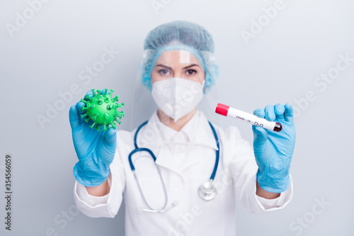 Photo of lady doc show covid bacteria blood probe tube demonstrate infecting process vaccine research clinic wear gloves mask coat facial plastic surgical cap isolated grey color background