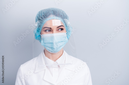 Closeup photo of attractive virologist doctor lady surgery operation save life look side dreamy wear medical gown coat mask facial plastic protect surgical cap isolated grey background