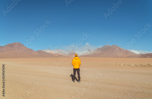  Tourist man hiking landscape mountain lake. Dry, Barren desert, snowcapped mountains wilderness. Mountain range view. Salt Flats, Uyuni, Bolivia. Copy space, Rocks, blue sky, nature, hiker