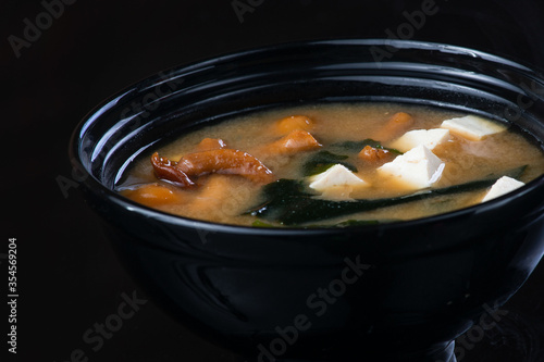 Japanese Soup With Chicken, Egg, Simeji Mushrooms and Eggplant On a Dark Background in a black plate. close up photo