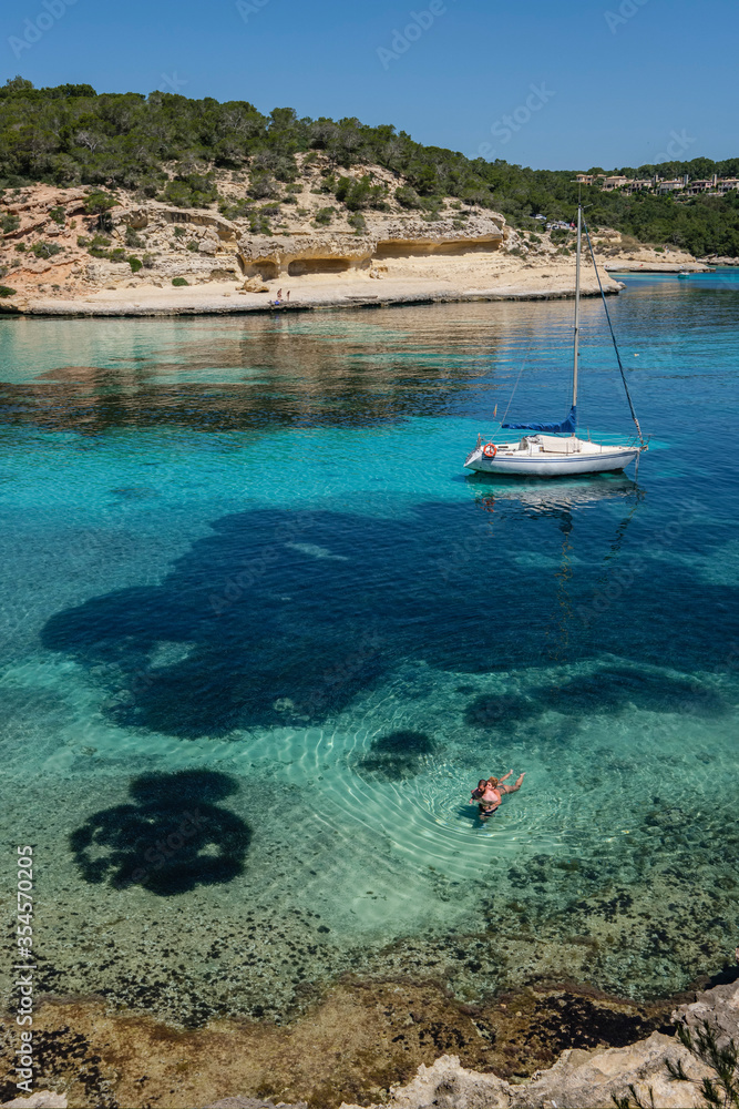 couple next to a moored sailboat, Cala Portals Vells, Calvia, Mallorca, Balearic Islands, Spain couple next to a moored sailboat, Cala Portals Vells, Calvia, Mallorca, Balearic Islands, Spain