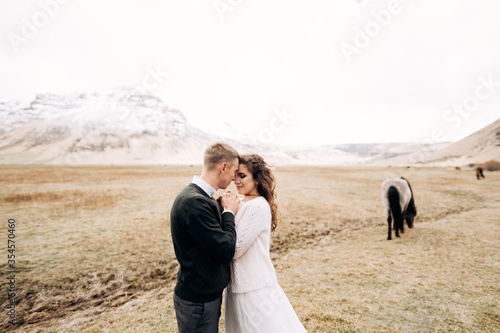 Destination Iceland wedding photo session with Icelandic horses. The groom hugged the bride s hands  in front of his face.