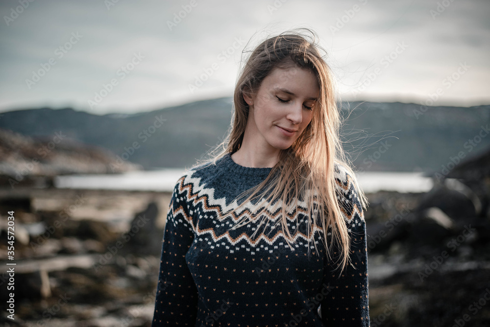 Romantic portrait of young blonde woman smiling and posing next to a fjord on a beautiful sunny spring day Romantic portrait of young blonde woman smiling and posing next to a fjord on a beautiful sunny spring day