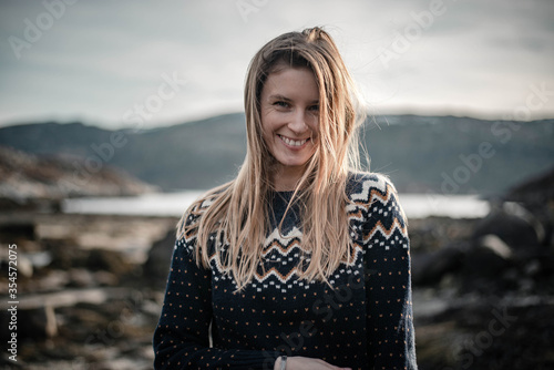 Horizontal photo of beautiful young woman is smiling to camera with hair naturally flying around her face