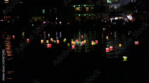 Glowing lanterns and the silhouettes of boats floating on the river  in the Hoi An  city, Vietnam