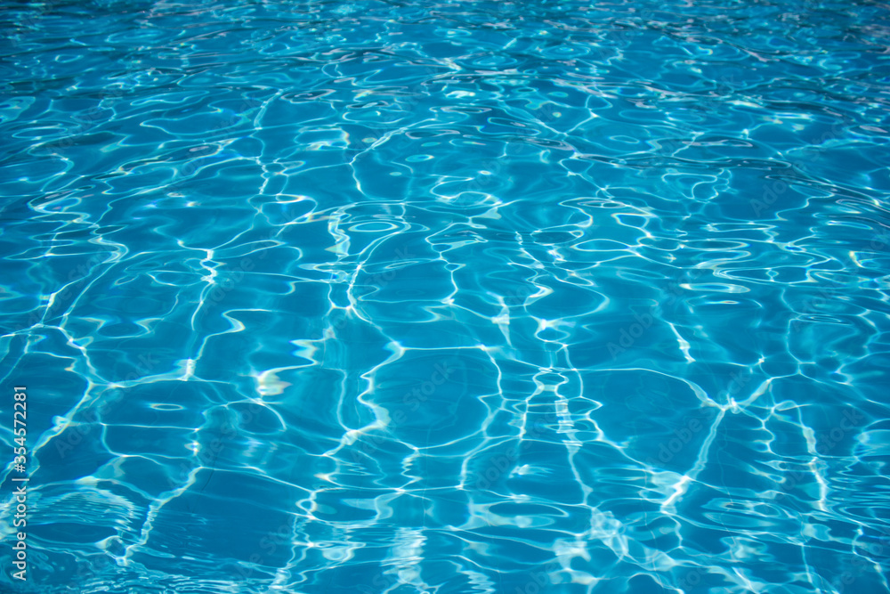 Blue and bright water in swimming pool with sun reflection. Motion of ripple water in pool.