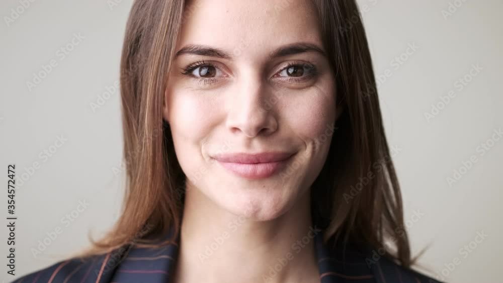 A close-up view of a smiling woman agrees with something while nodding standing isolated over white background in studio A close-up view of a smiling woman agrees with something while nodding standing isolated over white background in studio