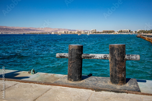 Gulf of Aqaba as seen from the port, Jordan. Some front line hotels and the crystal blue water of Red Sea, sunny winter afternoon, blurred concrete and metal equipment © lightcaptured