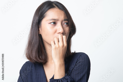 Unsure hesitant nervous young asian woman biting her fingernails.