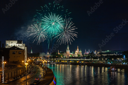 Green and white color circles of May 9 fireworks in dark night sky over Moscow cityscape with the Kremlin towers, reflection in the river, Saint Basil's Cathedral and floating bridge