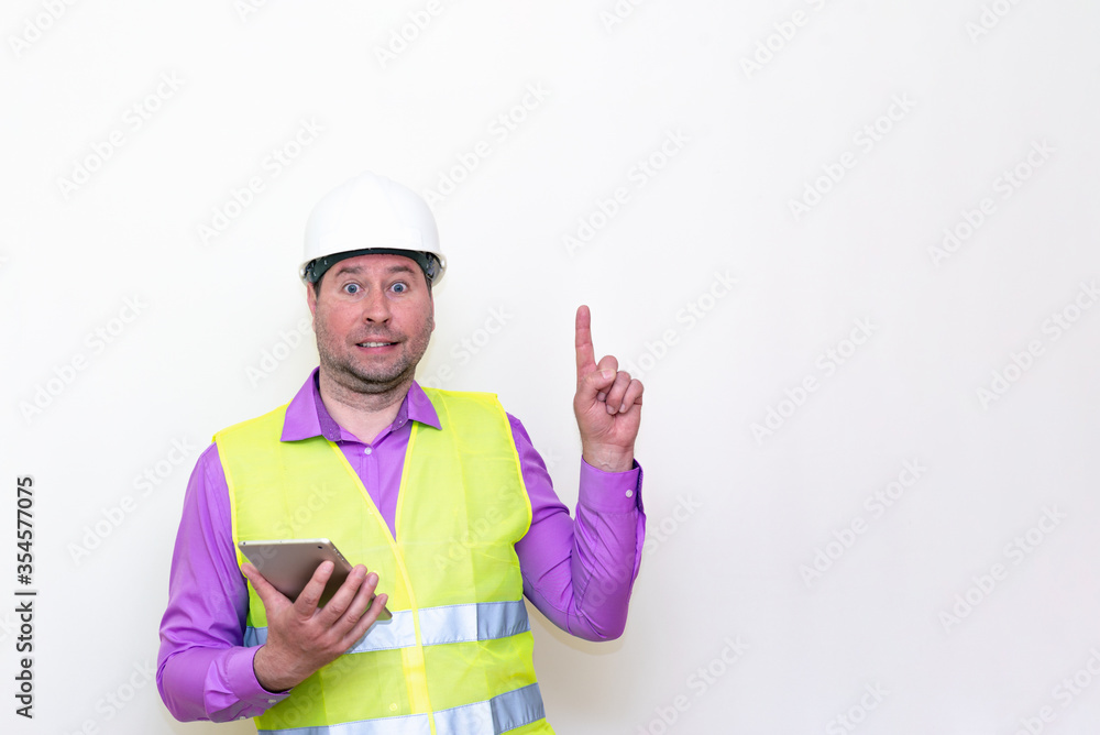 Construction builder wearing helmet yellow protective vest using wireless tablet and showing like or thumbs-up shocked poke up shows to you and victory gesture isolated on white background. Construction builder wearing helmet yellow protective vest using wireless tablet and showing like or thumbs-up shocked poke up shows to you and victory gesture isolated on white background.