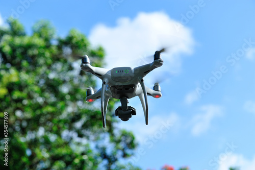 White drone with camera flying in summer