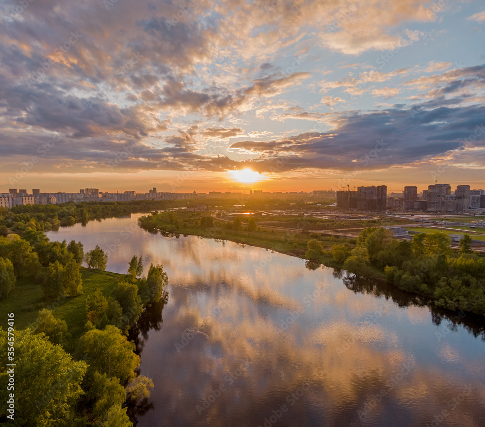 Beautiful sunset over the river, pink clouds are reflected in the water, summer nature in frame. Aerial photography