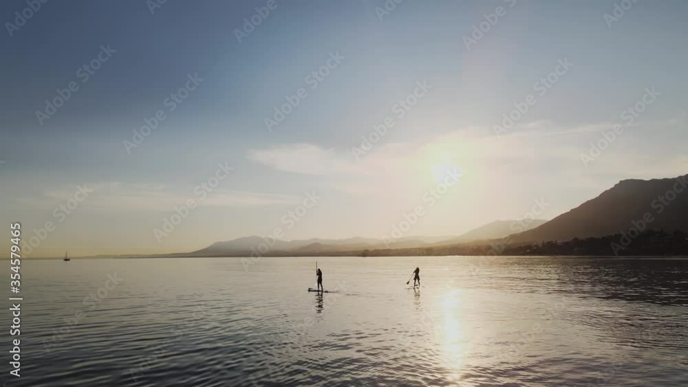 View over the ocean with two people paddling and right panning backwards View over the ocean with two people paddling and right panning backwards