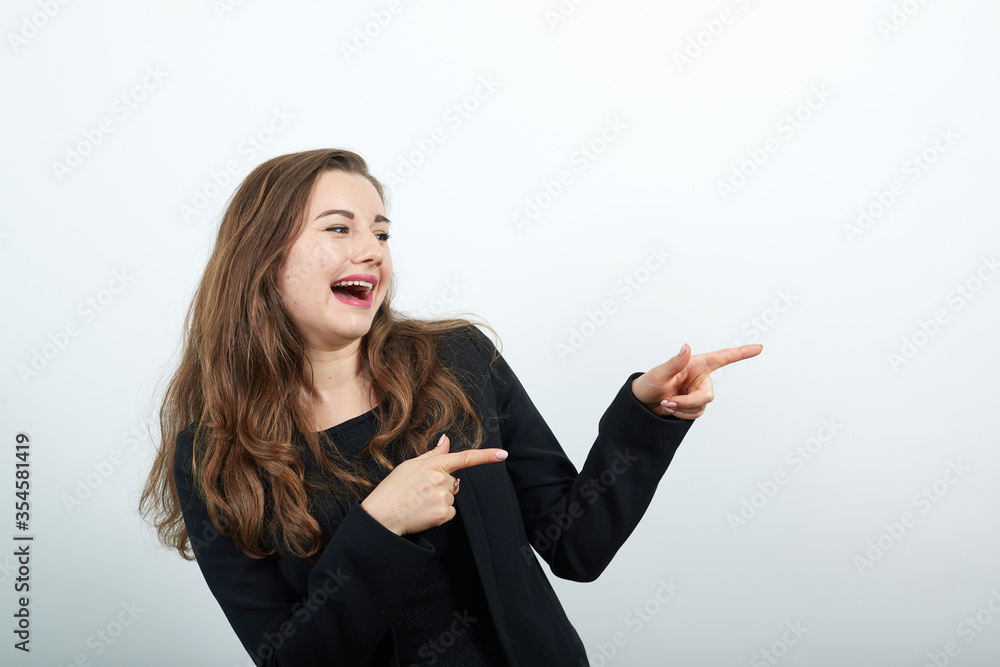 pointing her hand in the direction demonstrates your product showing direction copyspace pointing, young attractive woman brunette in in a black t-shirt and sweater on white background