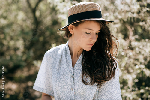 Portrait of a beautiful young brunette woman in a hat in the park