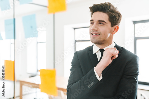 Image of pleased young businessman using stickers while working