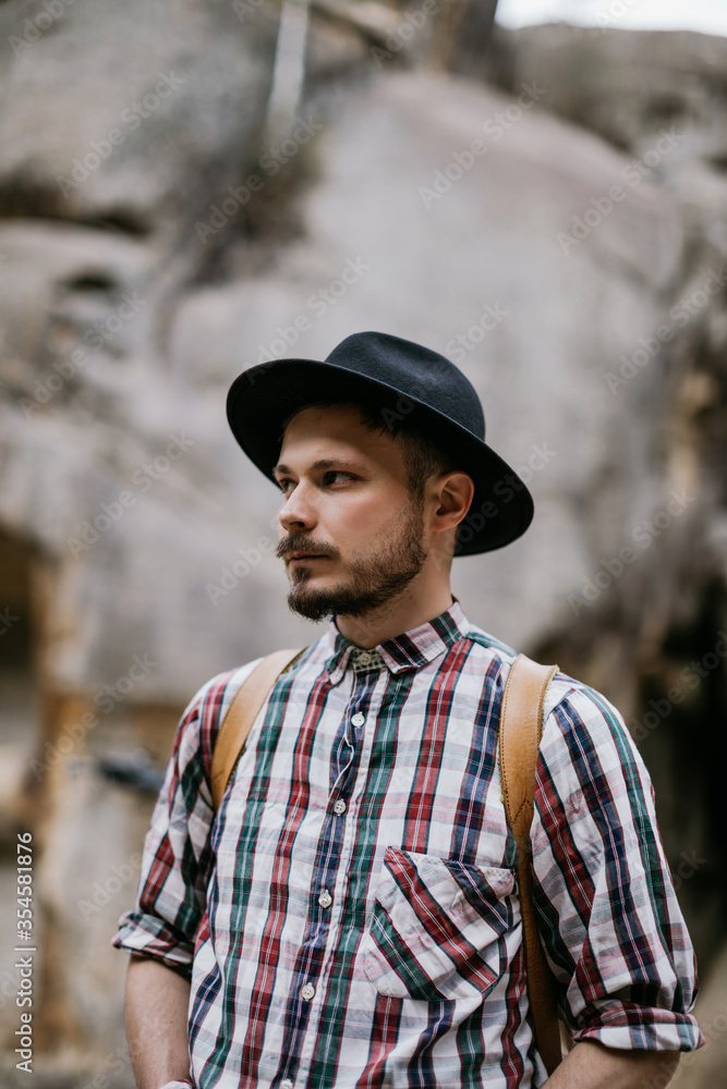 Portrait of a handsome young hipster man in a hat in the mountains Portrait of a handsome young hipster man in a hat in the mountains