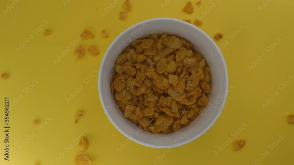 Breakfast cereals are poured into a white bowl, isolated on a yellow background, Healthy Breakfast, corn flakes. Breakfast cereals are poured into a white bowl, isolated on a yellow background, Healthy Breakfast, corn flakes.
