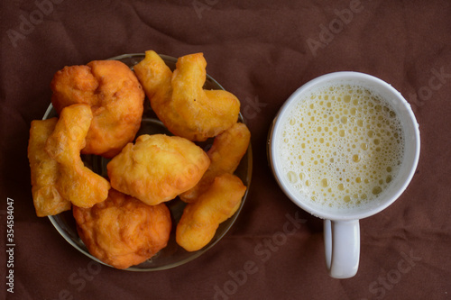 deep-fried doughstick on plate , dish and soymilk in a white glass both on brown background. photo